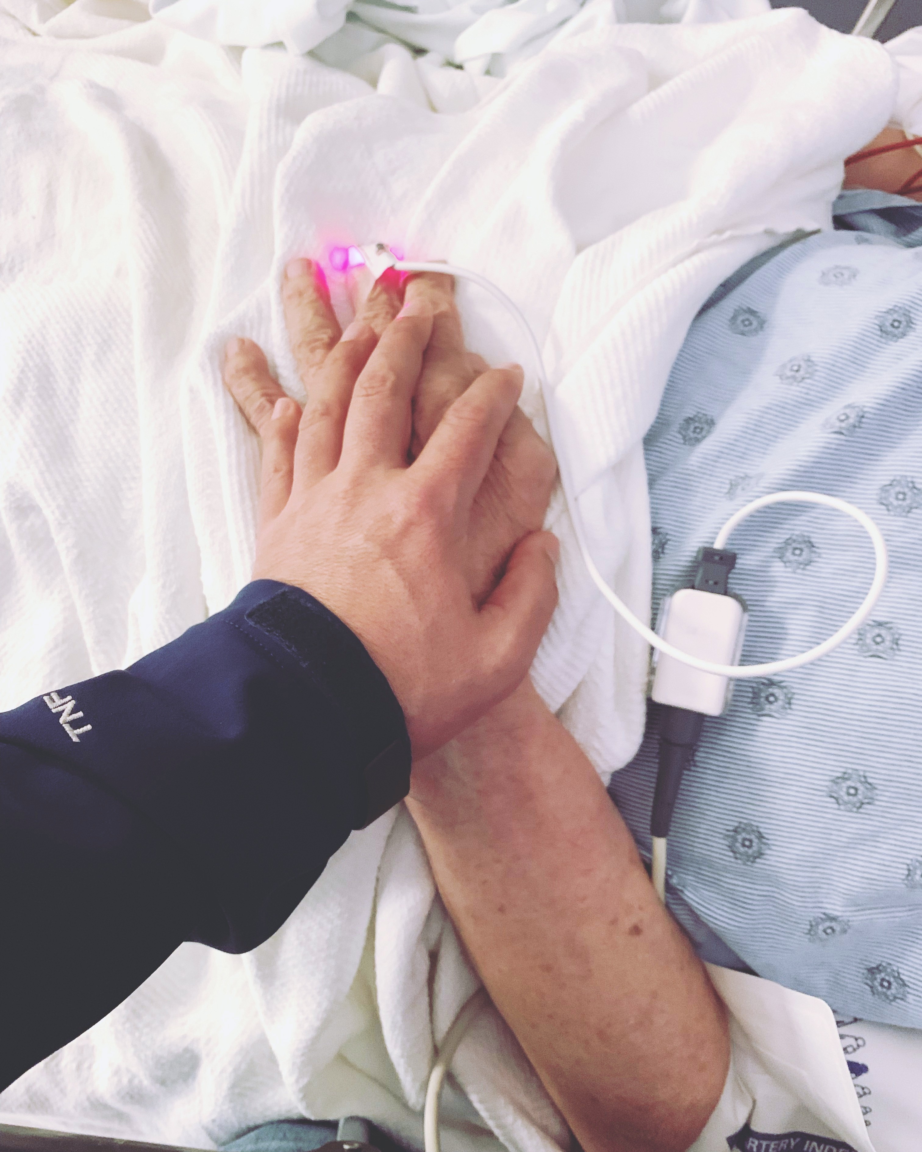 Holding the hand of a loved one at a hospital bedside
